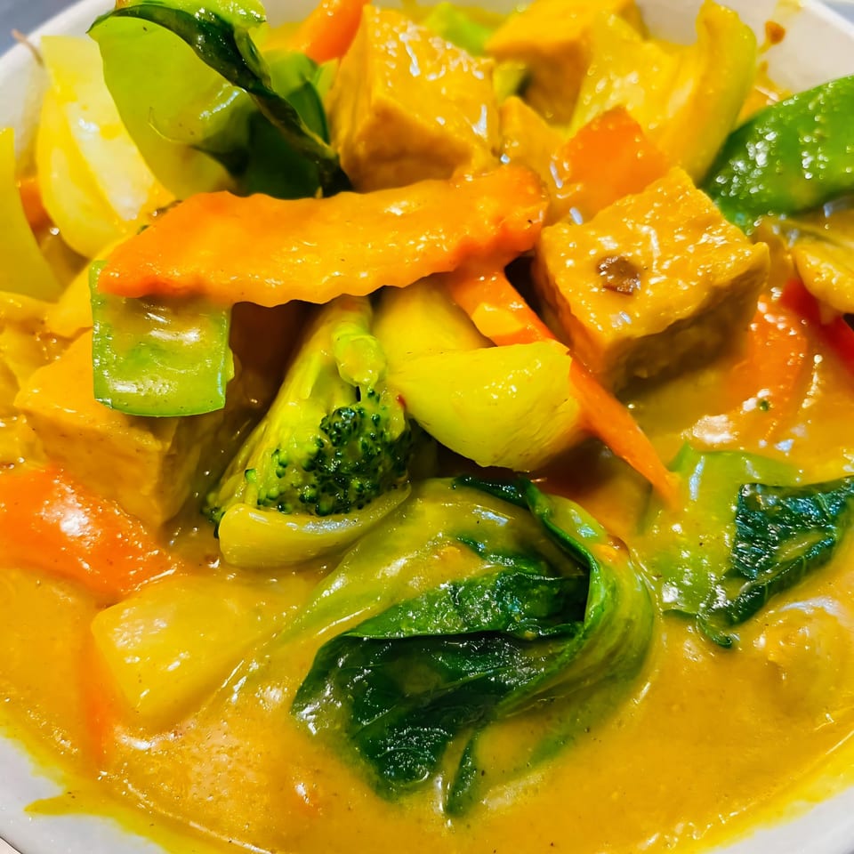 Close-up of Pho Boca's vibrant yellow curry with tofu, broccoli, carrots, and bell peppers.
